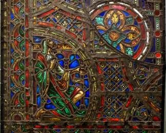 A Gothic Revival stained glass panel of the Prophet Joel.  Multi-color stained and leaded glass panels with reverse painted detail depicting a kneeling Prophet Joe within geometric and foliate borders.  Several cracked panels, some wear to paint and bowing.  36 x 37 1/2" high overall.
