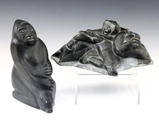 Two mid to late 20th century Inuit carved Soapstone figures.  Polished Dark Green and Black stone depictions of a Hunter with Seals.  Both with Canadian Igloo "Eskimo Art" certification tags at underside, longer figure signed "Levi Alasuak" (Inuit/Akulivik, b. 1951), taller figure signed Jeanie Shauk (Inuit/Kuujjuaraapik, b. 1920) in syllabics at underside.  Some surface wear.  10" long and 7 1/2" high.