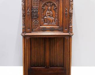 A turn of the century Gothic Revival Period carved Oak court cupboard.  Molded top with canted corners over one central door with carved tracery and figural panel, rope twist columns surmounted by carved Apostles, over an open lower shelf with linen fold carved back panel, Iron hinges and figural Apostle lock.  Original finish with some wear, minor damage and shrinkage.  27 1/2 x 19 1/2 x 54 1/2" high overall.