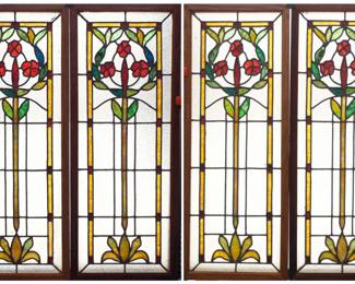 A set of four late 19th century American stained glass windows.  Multi-color stained and leaded glass panels depicting a scrolling rose design with slag and textured glass accents.  All with a few cracked panels or edge chips.  Each in Oak frames, 13 1/4 x 34" high overall.