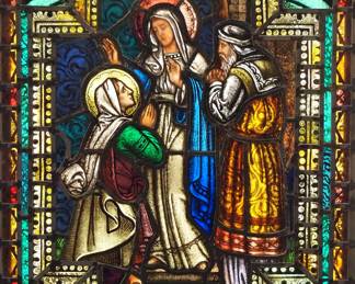 A Gothic Revival stained glass panel of The Visitation.  Multi-color stained and leaded glass panels with reverse painted detail depicting the Virgin Mary with St. Elizabeth and husband within geometric and foliate borders.  Soldered restorations to joinery at edges and in border, two cracks to panel of Mary's robe, some wear to paint.  20 1/4 x 25 3/4" high overall.