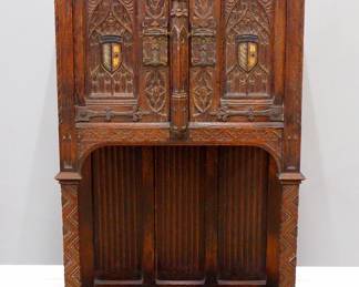 A turn of the century Gothic Revival Period carved Oak court cupboard.  Molded top over two doors with carved tracery, central carved spires, over a open lower shelf with linen fold carved back panel, original polychrome detail, Iron hinges and figural Apostle locks.  Old dark finish with some wear and minor damage.  33 x 15 1/2 x 58" high overall.