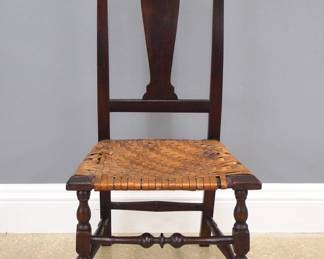 An early 18th century American Country Queen Anne side chair.  Maple construction with a shaped crest and vasiform splat, splint seat and turned legs terminating in pad feet, with a turned front stretcher.  Older refinishing with some wear, replaced splint on seat with some damage.  40 1/4" high overall.