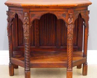 A turn of the century Gothic Revival Period carved Oak console table.  Shaped top with canted corners over an arched flat carved skirt and open lower shelf with linen fold carved back panel, on carved legs with rope twist columns surmounted by Apostle figures.  Older finish with minor wear, some shrinkage.  36 x 17 x 32 1/4" high overall.