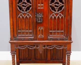 An early 20th century Gothic Revival carved Oak radio cabinet.  Molded top over over two doors with carved tracery and pierced Rose Window design, Iron hinges and lock, over an open lower with linen fold carved back panel and rope twist legs and stretcher base.  Opens to reveal an upper speaker compartment with lift-up door and lower pull out drawer with a "Sonora" radio and Brass dials.  Speaker with original "Dynamic" label at back.  Old finish with minor, small chip to door, radio untested.  36 1/2 x 19 1/2 x 54 1/4" high overall.