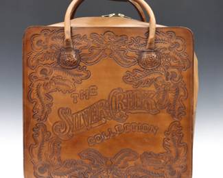 A 20th century Silver Creek Collection tooled leather suitcase.  Square form with two handles and hand-tooled Oak leaf decoration.  Some wear and discoloration.  18 1/2 x 8 x 23" high overall.
