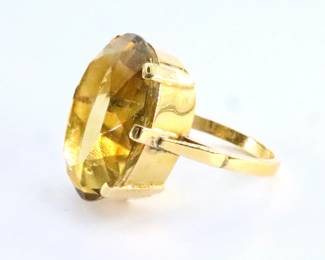 A mid 20th century 18k Yellow Gold and Citrine cocktail ring.  Faceted Citrine stone approx. 19.99 ct measuring 21 x 16 x 10mm in a contemporary style setting.  Marked "18k".  7.9 grams total.  Minor surface wear, appraisal notes slight inclusion to underside of Citrine.  Size 6 1/4.