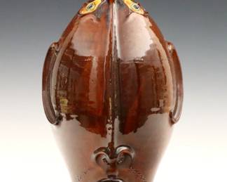 Roger Corn, American (Georgia), b. 1957.  A contemporary Folk Art pottery Face Jug with elongated features, strap handle and mottled Red/Brown glaze.  Signed "Roger Corn" and dated "2005" at underside.  Minor surface wear.  11 3/4" high.
