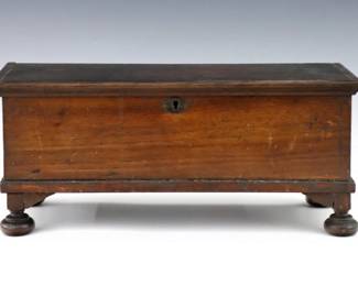 A 19th century American miniature blanket box.  Walnut construction with a hinged molded rim and turned feet.  Older, dark finish with some wear, minor shrinkage.  23 13/4 x 5 1/2 x 5 1/2 1/2" high overall.  NOTE: From the Collection of Connie Covent, "Sign of the Windsor Chair" Antiques, Clarkston, Michigan.