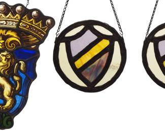 Three 19th century British Victorian Period Heraldic stained glass panels.  Multi-color stained and leaded glass, includes a pair of Armorial roundels with textured detail, and a Coat of Arms with reverse painted detail depicting a Rampant Lion with Crown.  Lion with several cracked panels, wear to paint.  Up to 11 1/2" high.