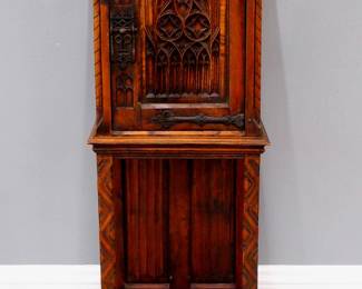 A turn of the century Gothic Revival Period carved Oak side cupboard.  Molded top over one central door with carved tracery flanked by rope twist columns, over an open lower shelf with linen fold carved back panel, Iron hinges and lock.  Old finish with some wear, minor damage and shrinkage.  19 x 15 1/2 x 48 1/2" high overall.