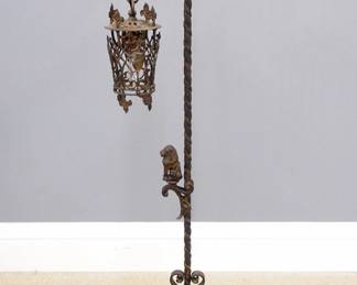 An early 20th century Gothic Revival Period floor lamp.  Cast Iron construction with Battle Axe form bridge and pierced lantern shade with Shield design, on a twisted stem with seated Lion finial and circular quatrefoil foot.  Wear to patina, some oxidation.  49 1/2" high.