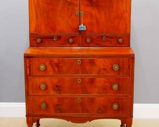 A 19th century American Country Sheraton secretary desk.  Mahogany construction with a two door upper section with fitted interior and two lower drawers on a base with fold out writing surface and pull out supports one three dovetailed drawers, shaped apron and tall turned legs.  Older refinishing with minor wear, replaced "leather' on slope, replaced Brass knobs.  18 x 39 x 60" high overall.