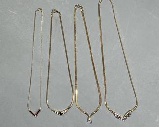 (4PC) ELEGANT COSTUME NECKLACES | Gold-toned costume necklaces with faux gemstones, including an unmarked necklace with a teardrop faux diamond, a necklace with ruby and diamond style pendant, and two Avon necklaces, one with amethyst style stones and one with an oval sapphire style stone
