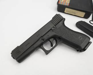 Make: Glock
Model: 17
Caliber: 9x19
Action: Semi
Barrel: 4.5
Bore: Shiny
Serial # LS600 US
The first-generation (Gen 1) Glock pistols are most notably recognized by their smoother "pebble finish" grip and finger groove-less frames. The Gen 1 frame pattern and design was used by Glock from 1982 through 1988 and pre-dates the checkered grip patterns used in the second generation of Glock pistols. The first Glock 17s imported to the US were serialized with an alpha-numeric (two-letter prefix followed by three numbers) stamped into the slide, barrel, and a small metal plate inserted into the bottom side of the polymer frame. This 17 has a serial number of LS600 US and comes with the iconic Glock “tupperware” case and two magazines. The pistol appears unfired and shows next to no signs of use or handling. 