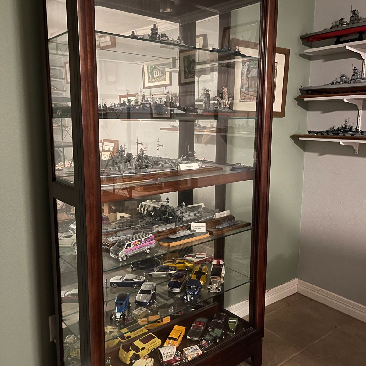 Curio cabinet full of models cars and ships.