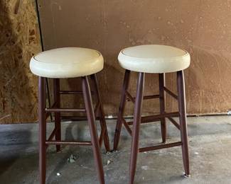 A pair of cream colored barstools with brown wooden bases.