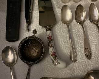 Selection of sterling silver spoons, strainer, and salt and pepper shakers; antique straight razor.