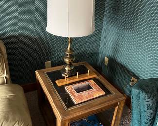 Glass-top end/accent table; brass table lamp; books.