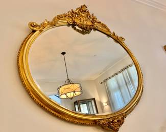$850 -Ornate gilt oval, beveled mirror (minor gilt pieces missing)  50" H, 52" W