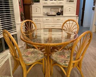 Round glass breakfast table with four tan chairs. 