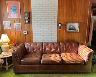 This brown leather sofa is in good shape.  On the wall are a few of the framed artwork items in the sale.