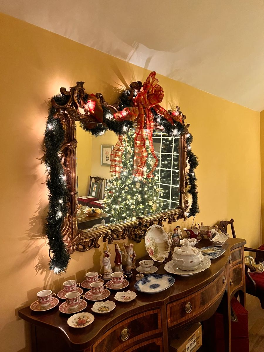 Dining Room | Lit garlands hang on a beautifully gilded English Chinoiserie replica mirror above the large Hepplewhite inlaid and banded sideboard c1915. 