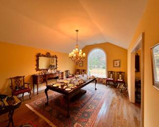 Dining Room | A stunning late 20th-century Henredon Chippendale dining set with ornately carved claw and ball feet and 8 heavily carved chairs upholstered in fine silk, an 8'x11' beautifully patinated antique tribal geometric rug, an inlaid and banded Hepplewhite sideboard, and a gilded English Chinoiserie replica mirror are the highlights of the well-appointed dining room.