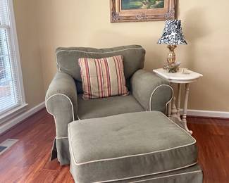 Matching club chair and ottoman, white vintage side table, gold frame art work.