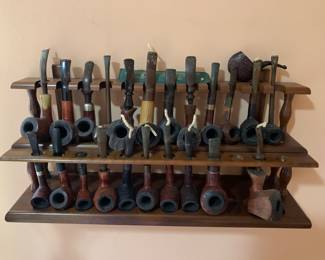 Two dozen vintage smoking pipes in this wall rack