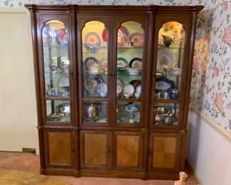 Lighted china cabinet with a collection of china, porcelain and glass, along with silver plate.