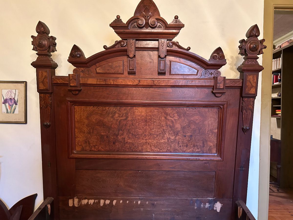 Large ornate antique bed with burl panels on the headboard and footboard and wooden side rails