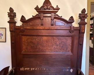 Large ornate antique bed with burl panels on the headboard and footboard and wooden side rails