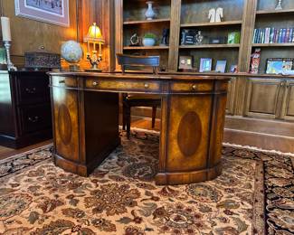 Late 1890s oval Partner’s desk in a beautiful mahogany. This extraordinary and extremely rare oval-shaped English partner's desk features beautifully figured mahogany and its original tooled leather top. Drawers and shelves are hidden behind doors that have been skillfully crafted and set on a convex surface. 