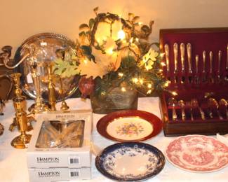 Table is full of silver plate, china plates, brass candlesticks and more.  