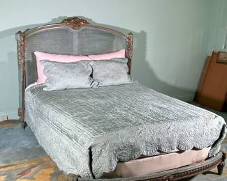 LOUIS XVI STYLE CARVED BED FRAME | Intricately carved French gilt and polychrome bed frame with curved & caned headboard with carved & gilt floral crest and mounts with intricate gilt carving around base. - l. 90 x w. 66 x h. 56.5 in

