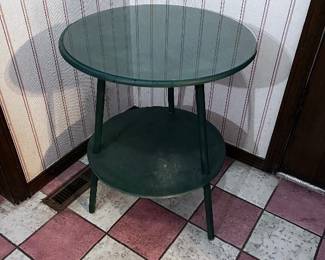 Green, three legged side table with glass top. 25" tall and 18" across