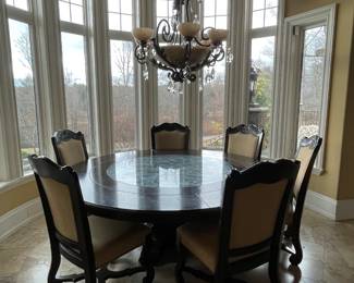 8 ft round extension table inset with decorative wrought iron circle and covered with glass, 6 chairs