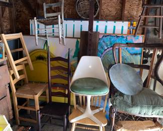 Tulip chair surrounded by many Vtg. Chairs, bed frames and Porcelli art