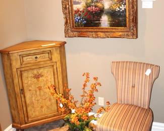 Corner cabinet, upholstered chair, beautiful painting and silk flower arrangement.