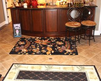 The bar area is full of area rugs, bar chairs, glassware and decorative objects.