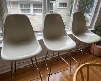 $1200 Three Eames counter height molded plastic stools in white.  26"w x 19"d x  40.5" h at the top of the back.  Currently online for $595 each plus tax and shipping.