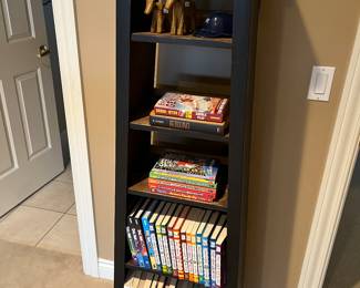 Narrow bookshelf; selection of books for young readers and sports books.