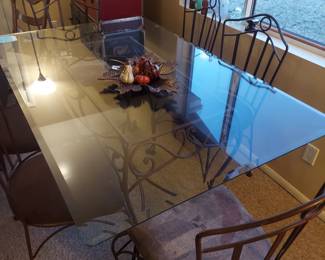 Glass top dining table with iron base and six upholstered chairs.