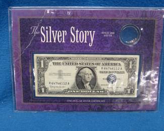 Lot 180. One $1 Silver Certificate enclosed in a display folder with tiny silver pellets and a history of the use of silver certificates in America.