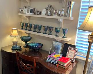 The antique mahogany desk has really been treated with love. It has glass top on it for protection. Sitting on the right side are special journals. The other side is showing off a collection of carnival glass.