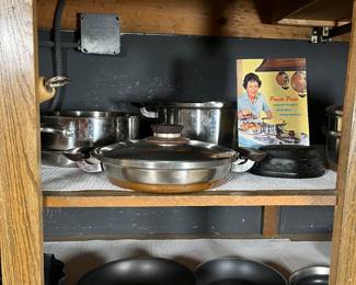 The top shelf features Presto Pride pots and skillets. These 1950 pots are featured on the front of Presto Pride's cookbook as seen in this picture.