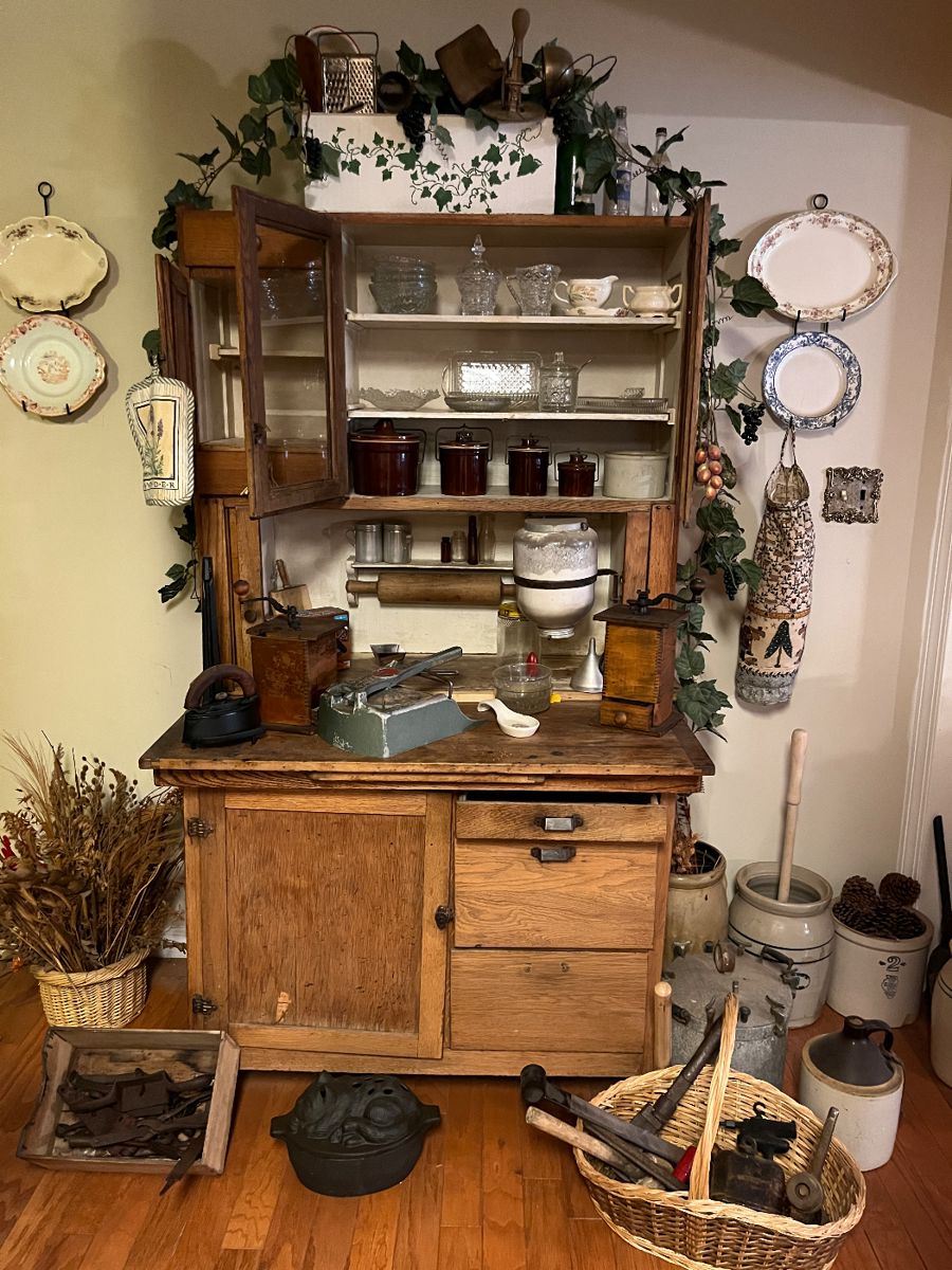 Very old Hoosier cabinet with history dating to circa early 1900.  Built in dough rolling pin and table. Vintage tools in boxes at the front, old kitchen utensils on the top.
