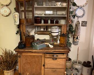 Very old Hoosier cabinet with history dating to circa early 1900.  Built in dough rolling pin and table. Vintage tools in boxes at the front, old kitchen utensils on the top.