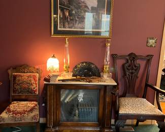 Another lighted book case, marble top.  Oil lamps on top, Victorian chairs.